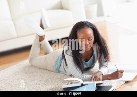 Frau liegend auf Teppich tun eine Buchbesprechung Stockfoto