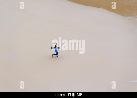 SANTANDER, Spanien - 11. März 2015: Lokalmatador walking mit einem Surfbrett am Strand ein Wintermorgen Stockfoto