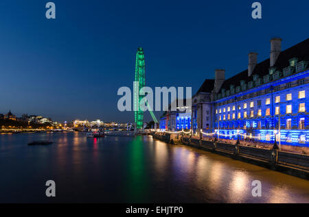 Das London Eye und die County Hall sind gegen einen nächtlichen Himmel beleuchtet und spiegelt sich in der Themse, London. Stockfoto