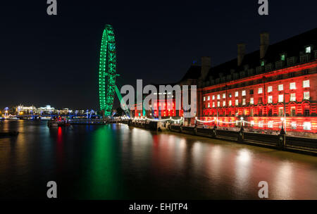 Das London Eye und die County Hall sind gegen einen nächtlichen Himmel beleuchtet und spiegelt sich in der Themse, London. Stockfoto