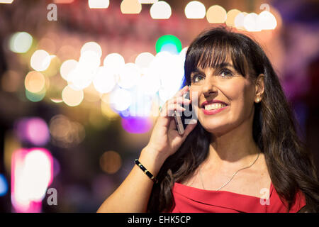 Eine Frau in ihrem 40 auf ihrem mobilen Gerät während einer Nacht Stockfoto