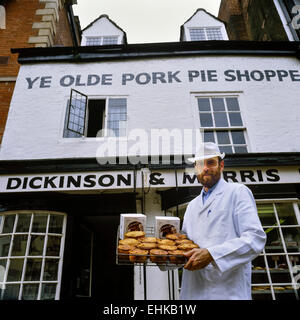 Ein Bäcker hält ein Tablett mit Melton Mowbray Schweinefleischpasteten & Melton Jagd Kuchen. Ye Olde Shoppe Pork Pie. Melton Mowbray. Leicestershire. Stockfoto