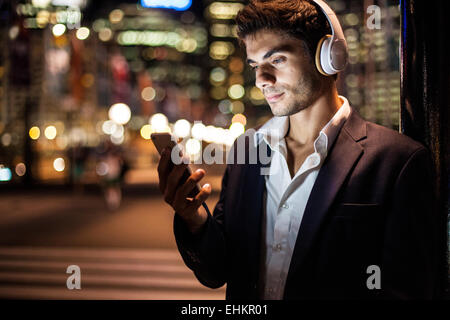 Ein junger Mann, Musik hören oder sprechen auf seinem Smartphone in der Stadt bei Nacht Stockfoto