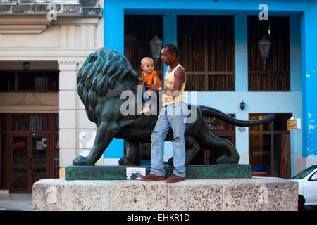 Vater und Sohn spielen auf der Löwenstatue auf dem Prado, Havanna, Kuba Stockfoto