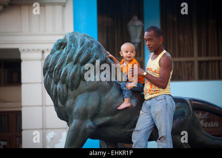 Vater und Sohn spielen auf der Löwenstatue auf dem Prado, Havanna, Kuba Stockfoto