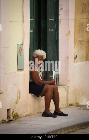 Eine alte Frau sitzt auf der Straße in Havanna, Kuba Stockfoto