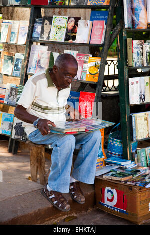 Ein Mann untersucht ein Buch auf einem Straßenmarkt in Plaza de Armas, Havanna, Kuba Stockfoto