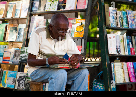 Ein Mann untersucht ein Buch auf einem Straßenmarkt in Plaza de Armas, Havanna, Kuba Stockfoto