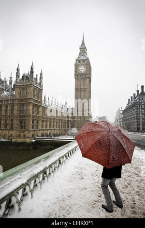 Ein Mann Unterstände unter einem Regenschirm in den Schnee, Westminster, London, Großbritannien Stockfoto