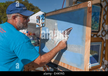 Ein Künstler mit Kreide auf einer Zeichnung auf einer Veranstaltung in Tavares, Florida setzt einen Stand für die Darstellung seiner Arbeit. Stockfoto