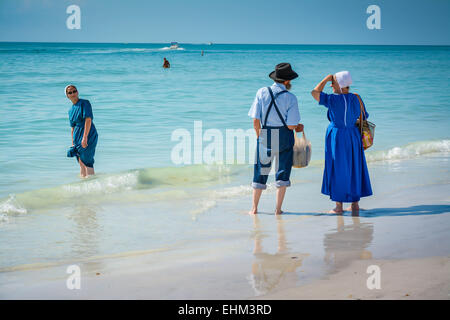 Drei amischen Leute, gekleidet in ihrer traditionellen Weise Paddel in der seichten Brandung am Siesta Key Beach in Sarasota, FL Stockfoto