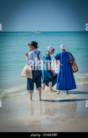 Drei amischen Leute, gekleidet in ihrer traditionellen Weise Paddel in der seichten Brandung am Siesta Key Beach in Sarasota, FL Stockfoto