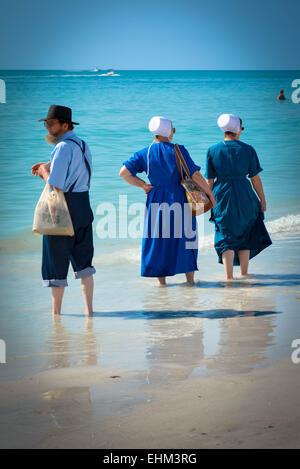 Drei amischen Leute, gekleidet in ihrer traditionellen Weise Paddel in der seichten Brandung am Siesta Key Beach in Sarasota, FL Stockfoto