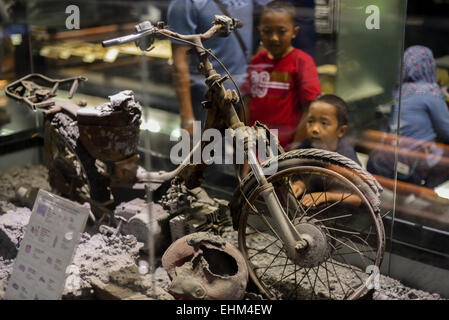 Bandung, Indonesien. 15. März 2015. Kinder zu beobachten, dass ein beschädigtes Motorrad getroffen pyroklastische Ströme, Geologie-Museum, Bandung, Indonesien. Das Artefakt stammt von 2010 Mount Merapi Ausbruch Website in Yogyakarta Provinz. Stockfoto