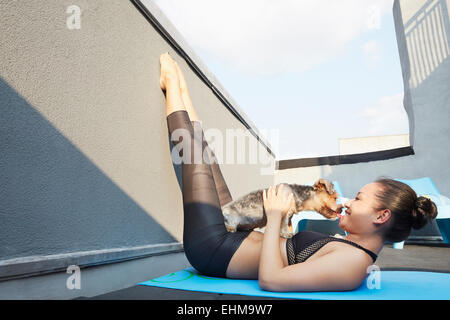 Chinesische Frau praktizieren Yoga mit Hund auf deck Stockfoto
