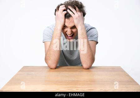 Jungen Mann sitzt am Holztisch verärgert Stockfoto