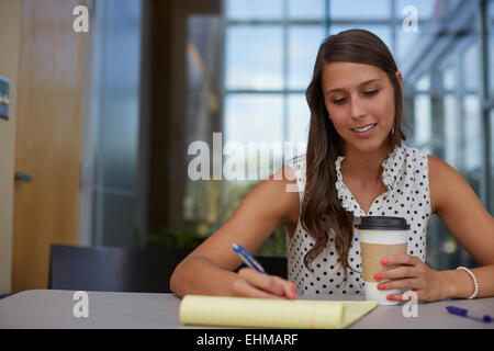 Gemischte Rassen Geschäftsfrau schreiben auf Merkzettel am Schreibtisch Stockfoto