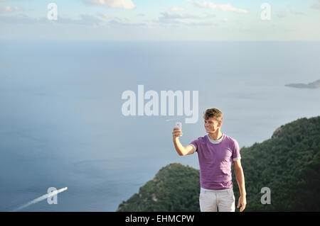jungen Mann nehmen Selfie auf einem Berg über Meer Lächeln Stockfoto