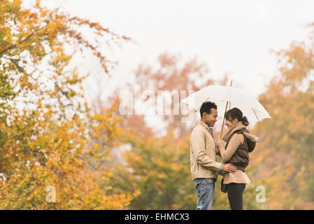 Paar stehend mit Schirm im park Stockfoto