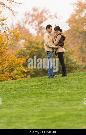 Paar stehend mit Schirm im park Stockfoto