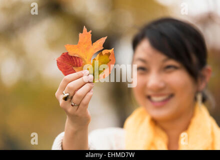 Asiatische Frau bewundern Herbst Blätter im freien Stockfoto
