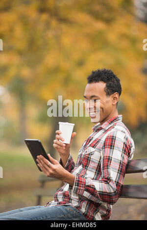 Gemischte Rassen Mann mit digital-Tablette auf Parkbank Stockfoto