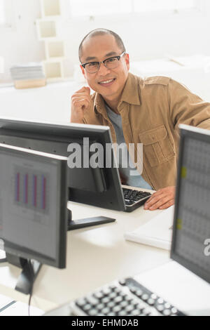 Koreanischer Geschäftsmann lächelnd am Computer am Schreibtisch Stockfoto