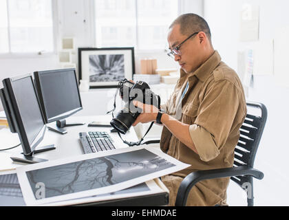 Koreanische Fotograf mit Kamera am Schreibtisch Stockfoto