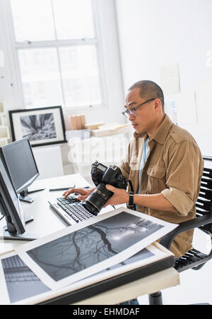 Koreanische Fotograf mit Computer am Schreibtisch Stockfoto