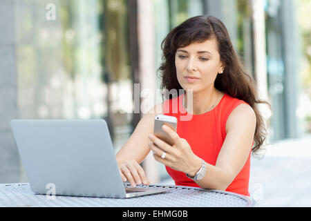 Kaukasische Geschäftsfrau mit Laptop und Handy im freien Stockfoto