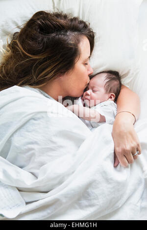 Erhöhte Ansicht der Mutter küssen Baby im Bett Stockfoto