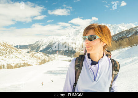 Erwachsene weibliche Skifahrer mit Rucksack und eine Sonnenbrille mit Glück an einem sonnigen Tag im Skigebiet von La Thuile, Aosta-Tal. Stockfoto