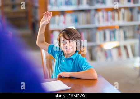 Student hob seine Hand in Bibliothek Stockfoto