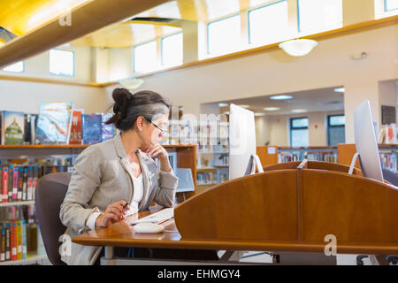 Ältere Frau kaukasischen über Computer in der Bibliothek Stockfoto