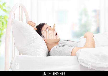 Mann mit einer Wäscheklammer auf der Nase zu Hause schlafen Stockfoto