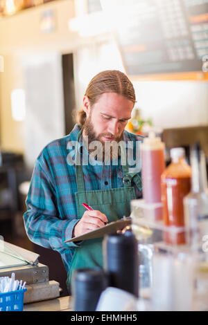 Kaukasische Server schreiben in Zwischenablage im café Stockfoto