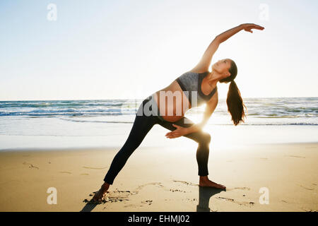 Hispanic schwangere üben Yoga am Strand Stockfoto