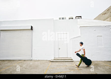 Gemischte Rassen Musiker Gitarre Tragetasche auf Bürgersteig Stockfoto