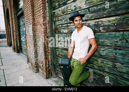 Gemischte Rassen Musiker halten Gitarrenkoffer in der Nähe von Industriegebäude Stockfoto