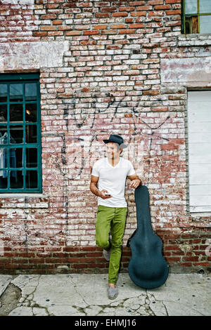 Gemischte Rassen Musiker mit Gitarrenkoffer mit Handy Stockfoto