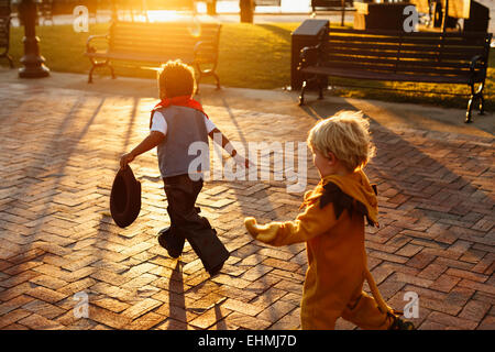 Jungs spielen in Kostümen auf Bürgersteig Stockfoto