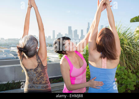 Lehrer helfen Yogaschüler in der Klasse auf städtischen Dach Stockfoto