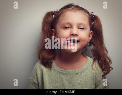 Wunderschönes kleines Mädchen zeigt die Zunge Grimassen. Closeup Vintage Porträt Stockfoto