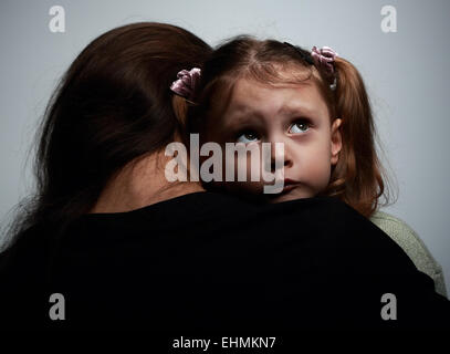 Denken traurig Tochter umarmt ihre Mutter und blickte auf dunklem Hintergrund Stockfoto