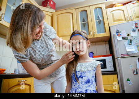 Mutter macht Tochter Frisur in der Küche Stockfoto