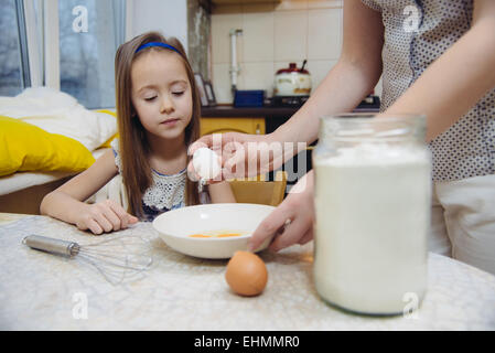 Kleine Mädchen den Teig für Pfannkuchen schlagen Stockfoto