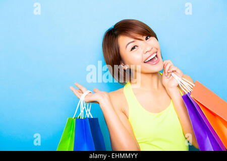 glückliche junge Frau mit Einkaufstüten vor blauem Hintergrund Stockfoto