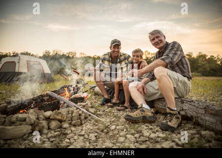 Drei Generationen von kaukasischen Männer Hotdogs über Lagerfeuer rösten Stockfoto