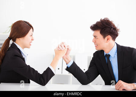 Mann und Frau Armdrücken auf Schreibtisch im Büro Stockfoto
