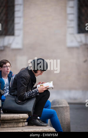 Ein weiblicher Touristen liest einen Reiseführer in Piazza di Santa Maria Trastevere, Rom, Latium, Italien. Stockfoto